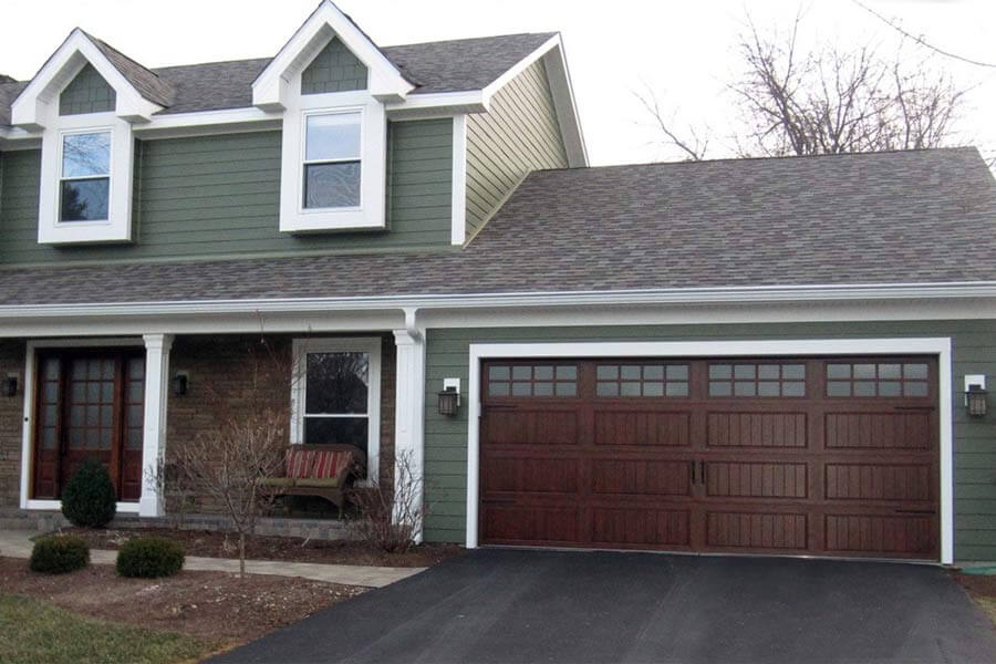 Siding installation professional securing vinyl panels on the exterior wall of a residential home.