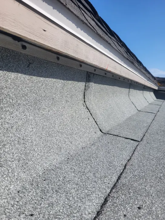 Gutter installation technician attaching a new aluminum downspout to a home's roofline.