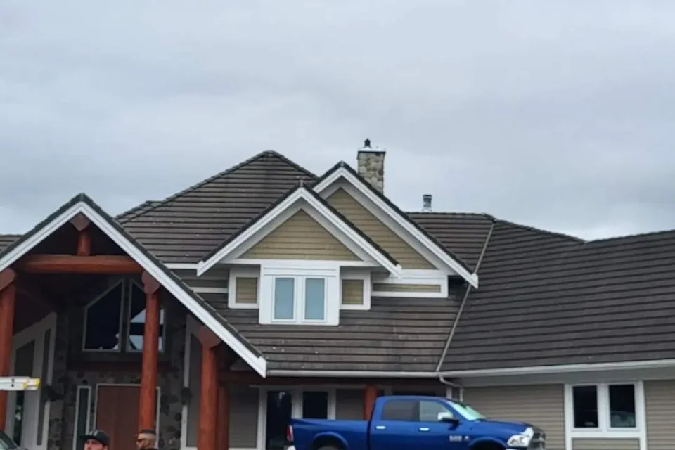 Roofing service team repairing shingles on a residential home under sunny weather.